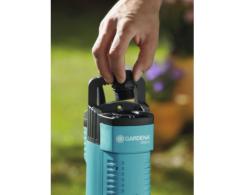 Eine Hand schraubt einen Anschluss auf eine Gardena 6000/5 Gartenpumpe.