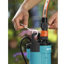 Person befestigt eine Gardena Tauchdruckpumpe mit einem Seil an einem Schlauch