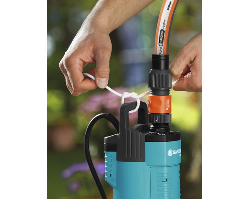 Person befestigt eine Gardena Tauchdruckpumpe mit einem Seil an einem Schlauch