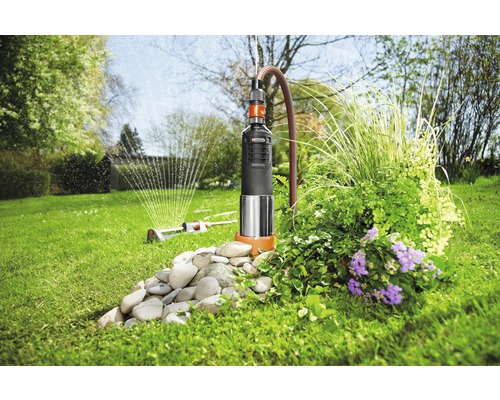 Gartenszene mit Tauchdruckpumpe zur Gartenbewässerung und Gartensprenger im Einsatz.