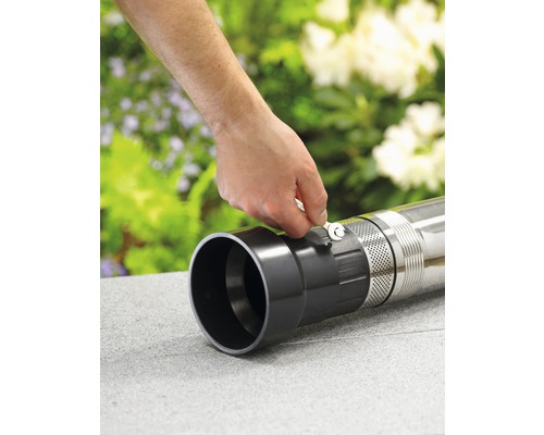 Eine Hand befestigt mit einem Schraubenschlüssel ein Rohr an einer Gartenpumpe.