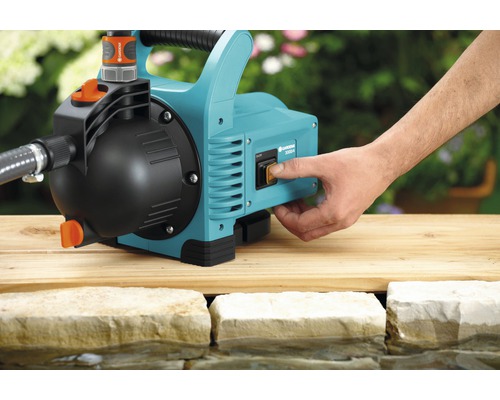 Gartenpumpe im Einsatz mit Hand am Schalter