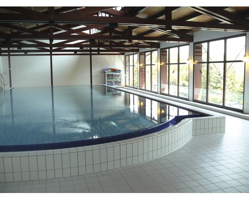 Piscine intérieure avec sol carrelé et plafond à poutres apparentes en bois