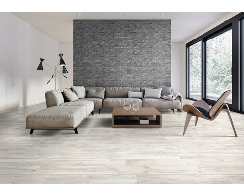 Wohnzimmer mit grauer Ziegelwand, Sofa, Couchtisch und hellem Holzboden