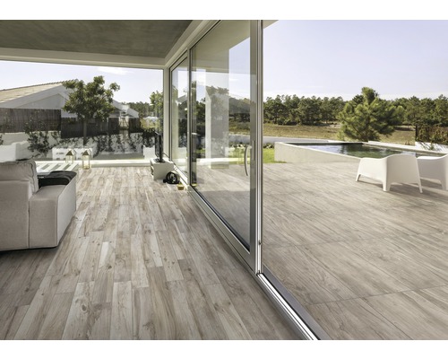 Heller Wohnbereich mit Holzoptikfliesen und Schiebetüren zum Garten mit Pool