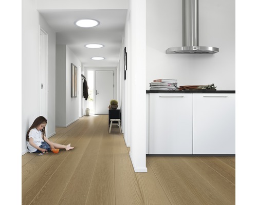 Couloir lumineux avec plancher en bois, fenêtres de toit et enfant jouant