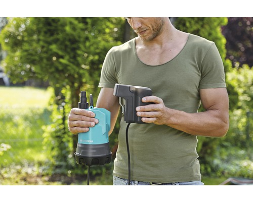 Mann hält eine Gardena Schmutzwasserpumpe mit Batterie in der Hand