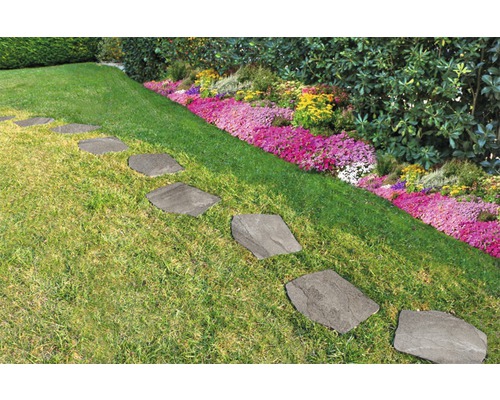 Trittplatten aus Stein im Gartenweg zwischen Rasen und Blumenbeet