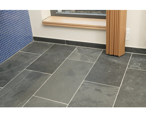 Badezimmer mit Bodenfliesen und blauer Wandfliese.