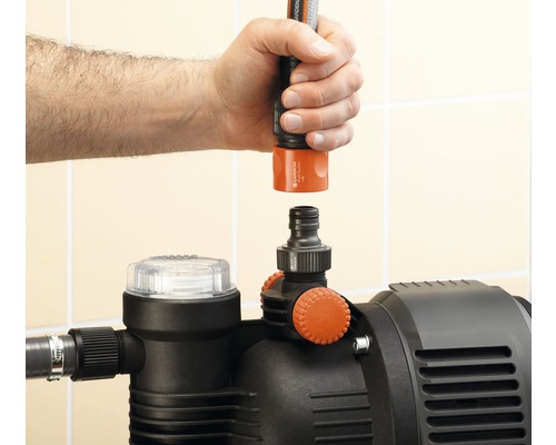 Main raccordant un tuyau d''arrosage à une pompe de jardin