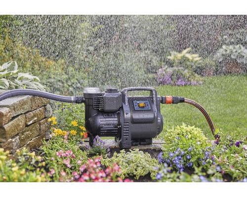 Gartenpumpe mit Schläuchen im Betrieb in einem Blumenbeet