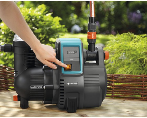 Gartenpumpe mit einer Hand am Einschaltknopf für die Wasserversorgung im Garten