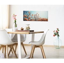 Salle à manger avec table en bois, chaises blanches et tableau de fleurs au mur