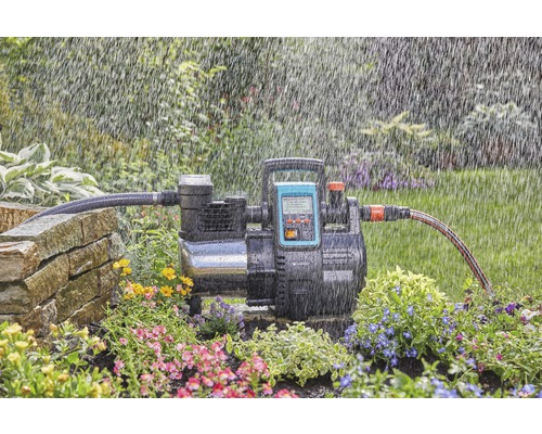 Gartenbewässerungsszene mit einem Hauswasserwerk inmitten von Blumenbeeten