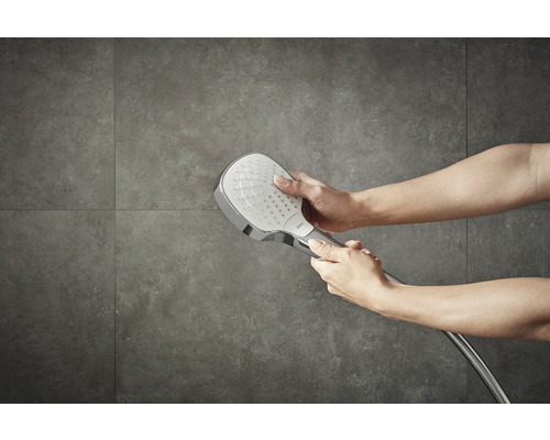 Handbrause aus Metall mit Brauseschlauch wird von zwei Händen gehalten