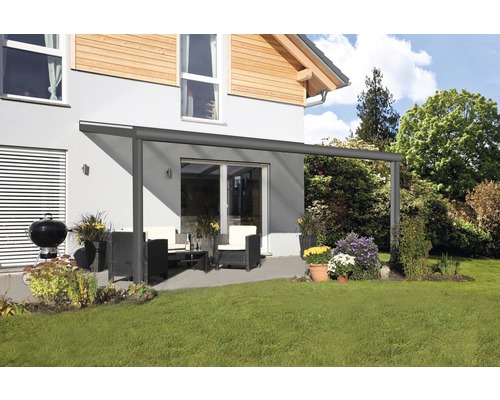 Auvent de terrasse avec mobilier de jardin et barbecue sur une pelouse devant une maison