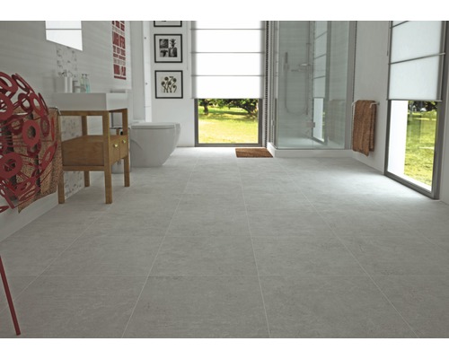 Salle de bain lumineuse avec carrelage gris, toilettes, lavabo et douche