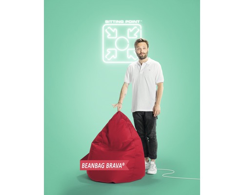 Un homme présente un pouf rouge Brava