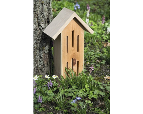 Insektenhotel aus Holz im Garten zwischen Pflanzen