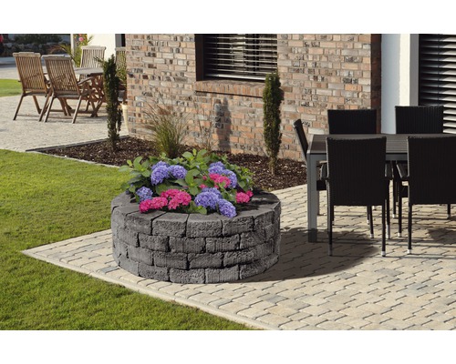 Jardinière ronde en pierre avec des plantes dans le jardin