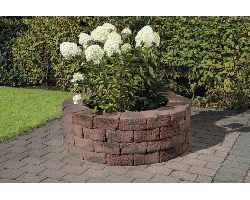 Jardinière ronde en briques avec plante fleurie dans le jardin