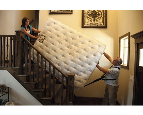 Deux personnes montent un matelas dans l''escalier
