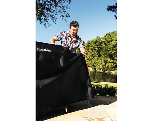 Homme plaçant une housse de protection sur un barbecue à l''extérieur avec le logo Char-Broil
