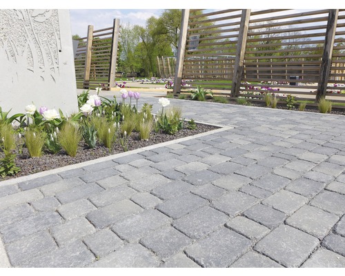 Gepflasterter Weg mit dekorativen Blumen und Holzzäunen im Garten