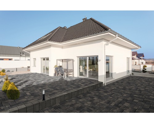 Einfamilienhaus mit dunklem Dach und gepflasterter Terrasse