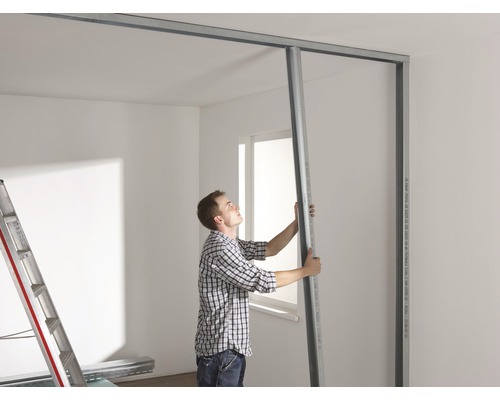 Mann montiert Metallrahmen für Trockenbauwand in einem Raum