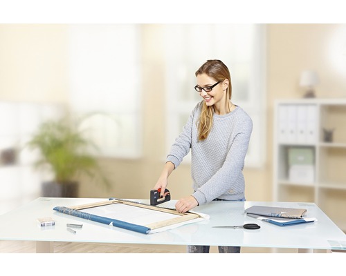 Une femme fixe une toile sur un châssis à l''aide d''une agrafeuse