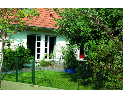 Une clôture grillagée verte avec portail entoure un jardin devant une maison.