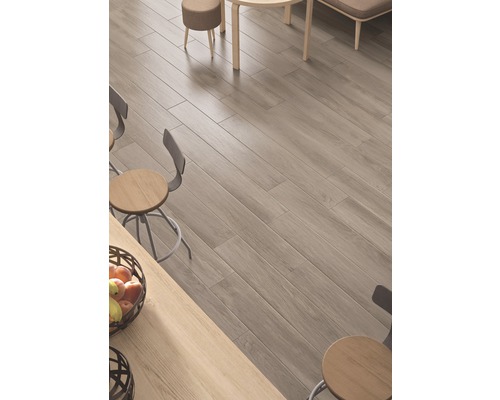 Helles Interieur mit Holzoptikfliesen auf dem Boden und Sitzgelegenheiten.