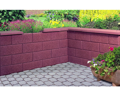 Angle d''un mur de jardin en parpaings avec recouvrement en pierre et pavés dans le jardin