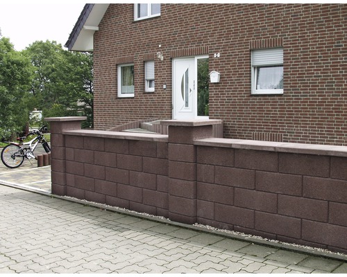 Eine Gartenmauer aus Mauersteinen vor einem Haus.