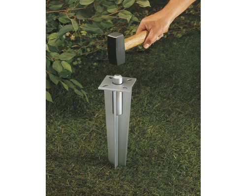 Einschlagbodenhülse aus Metall wird mit einem Hammer in den Boden eingeschlagen.