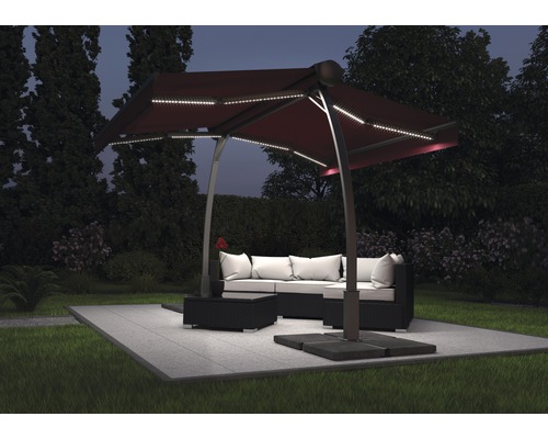 Scène de jardin avec un parasol excentré avec éclairage LED au-dessus d''un ensemble de salon