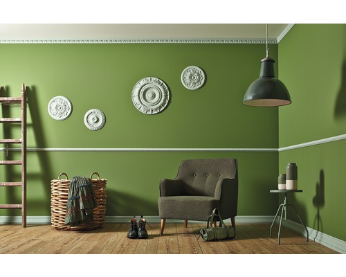 Séjour avec fauteuil, lampe, échelle et articles de décoration devant un mur vert