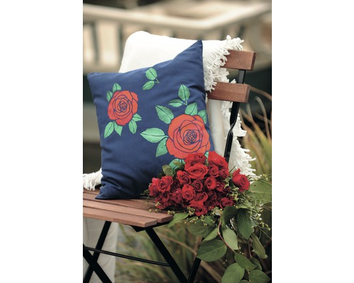 Dekoratives Kissen mit Rosenmuster auf einem Stuhl mit Blumenstrauß