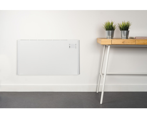 Wandmontierter, weisser Heizkörper neben einem Schreibtisch mit Pflanzen