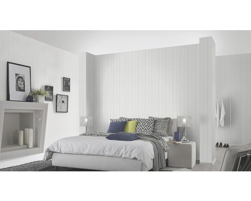 Helles Schlafzimmer mit Bett, Nachttisch, Dekoration und gestreifter Tapete