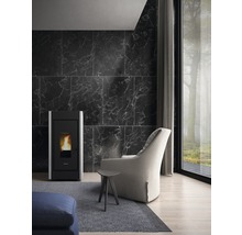 Salon avec poêle à pellets, fauteuil et petite table sur un tapis gris