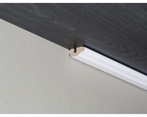 Plinthe en bois fixée à un mur et à un plancher en bois foncé