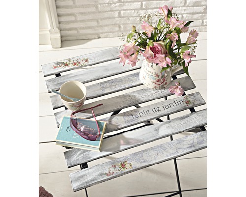 Dekorativer Gartentisch mit Blumenvase, Tasse, Buch und Brille