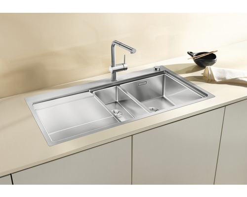 Edelstahlspüle mit Abtropffläche und zwei Becken in einer hellen Küche.