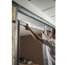Un homme installe une cloison sèche avec des profilés métalliques dans une pièce.