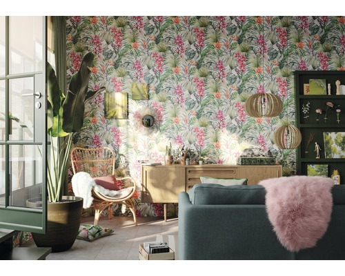 Salon avec papier peint jungle, canapé, fauteuil et meubles en bois pour une ambiance lumineuse.