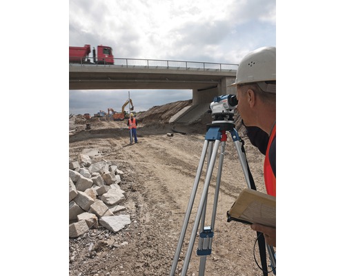 Ouvriers du bâtiment mesurant un chantier avec un niveau sous un pont.