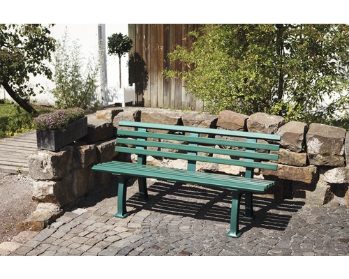 Banc de jardin en métal devant un mur de pierre