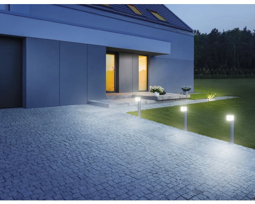 Beleuchteter Außenbereich eines Hauses mit Rasen und Steinweg